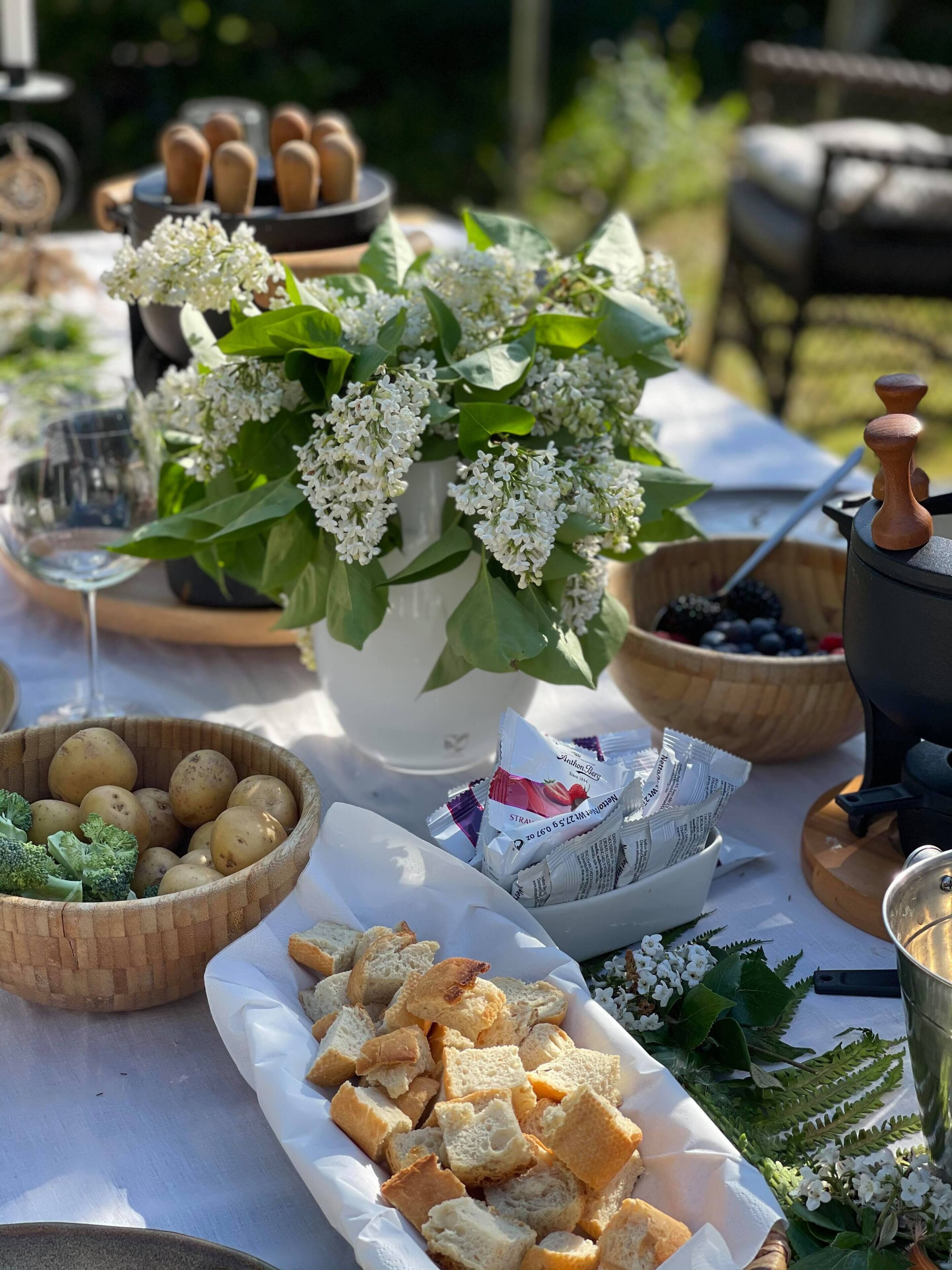 A table set with various food items, including bread, potatoes, and a bowl of strawberries.