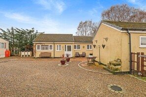 A two-story building with a gravel courtyard, a bench, and potted plants. - Teddy`s Cottage - North East Escapes (Beamish)