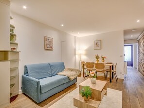 A modern living room with a blue sofa, a dining table with chairs, and a coffee table with a plant. - Atelier Parisien - 4P - Montparnasse Station (Paris)