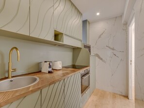 A modern kitchen with a wooden countertop, stainless steel sink, and a built-in oven. - Atelier Parisien - 4P - Montparnasse Station (Paris)