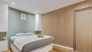 A modern bedroom with a bed, bedside tables, and a wooden slat wall.