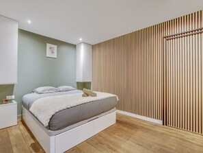 A modern bedroom with a bed, bedside tables, and a wooden slat wall. - Atelier Parisien - 4P - Montparnasse Station (Paris)