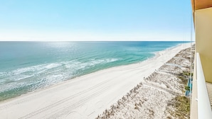 Blick auf den Strand vom Balkon aus, strahlend blauer Himmel.