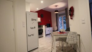 Una cocina moderna con armarios blancos, una mesa de comedor con camino de mesa geométrico y una pared de acento roja.
