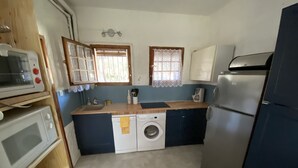 Une cuisine compacte équipée d’un lave-linge, d’un four à micro-ondes et d’un réfrigérateur.