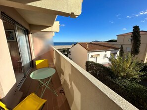 A balcony with a table and chairs, overlooking a beach and neighboring buildings. - Studio with balcony and parking by the beach (Argelès-sur-Mer)