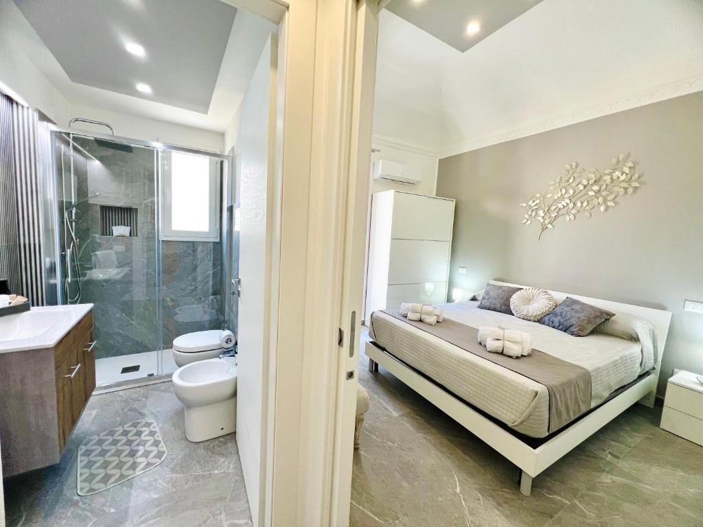 Une chambre à coucher moderne avec un lit, une table de chevet et un espace douche.