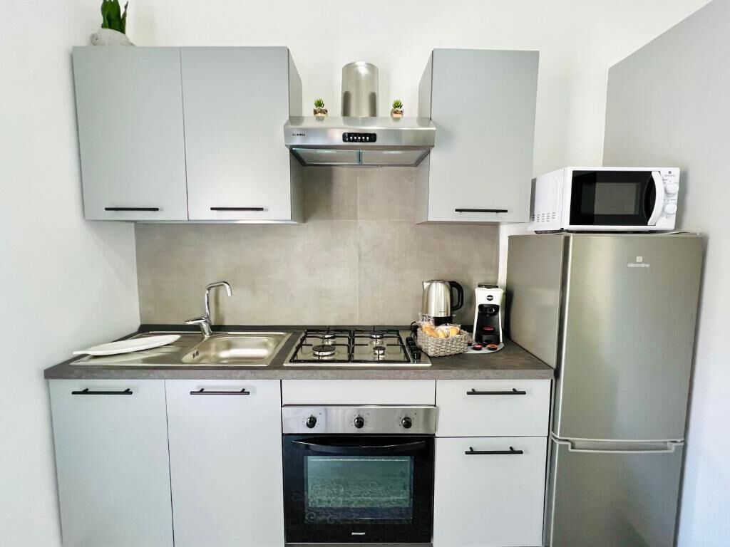 Une cuisine de taille réduite équipée d’une cuisinière à gaz, d’un four, d’un four à micro-ondes et d’un réfrigérateur.