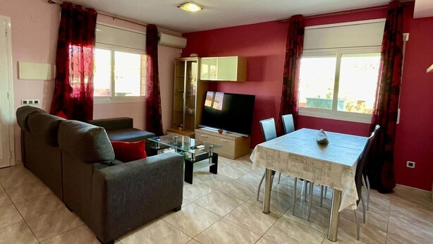 Sala de estar com sofá, televisão e mesa de jantar.