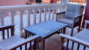 Um pátio com forno de tijolos, balaústres brancos e mobiliário de madeira.