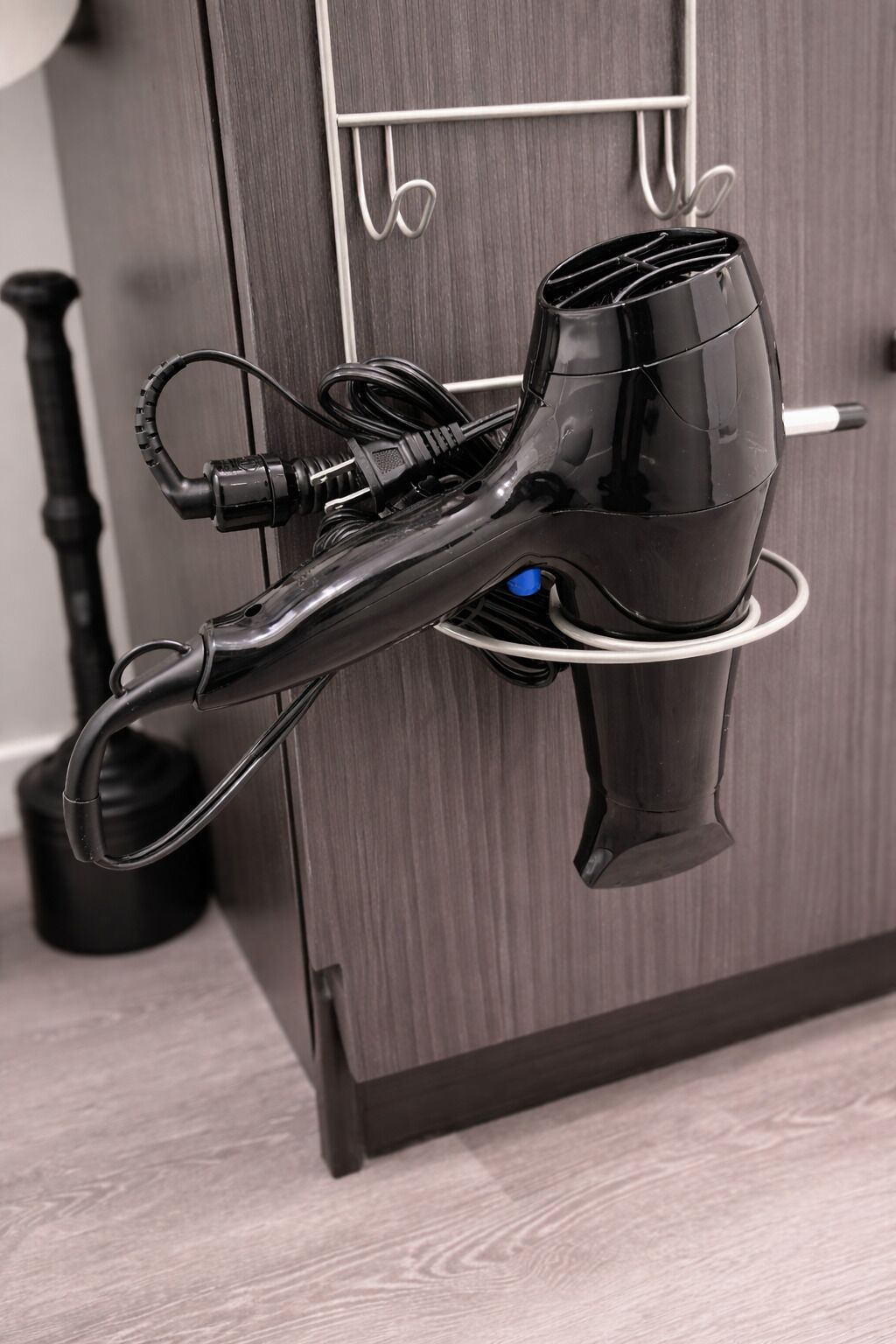 A hair dryer mounted on a wall with a cord and a plug.