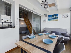 A compact living space with a dining table, sofa, and staircase leading to an upper level. - Studio Mezzanine for 6, Pets, Parking, Sea View (Marseillan-Plage)