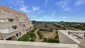 Um edifício residencial com várias varandas, área de estacionamento e vista para o mar.