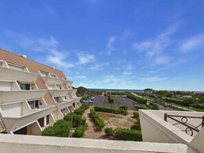 Un edificio residencial con varios balcones, un área de estacionamiento y vista al mar.