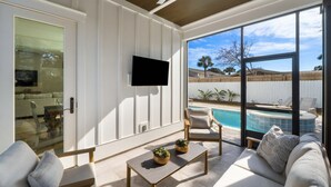 Ein modernes Wohnzimmer mit Blick auf einen Pool, einem Flachbildfernseher und einer gemütlichen Sitzecke.
