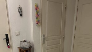 A hallway with a wooden shelf unit, a door, and a small table with a decorative item. - Bright private bedroom with desk  (Lyon)