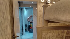Een slaapkamer met een stapelbed, een deur naar een badkamer en een behang met patroon.