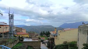 A view of a town with buildings, a church, and mountains in the background. - La Locanda b&b Dandana (Orgosolo)