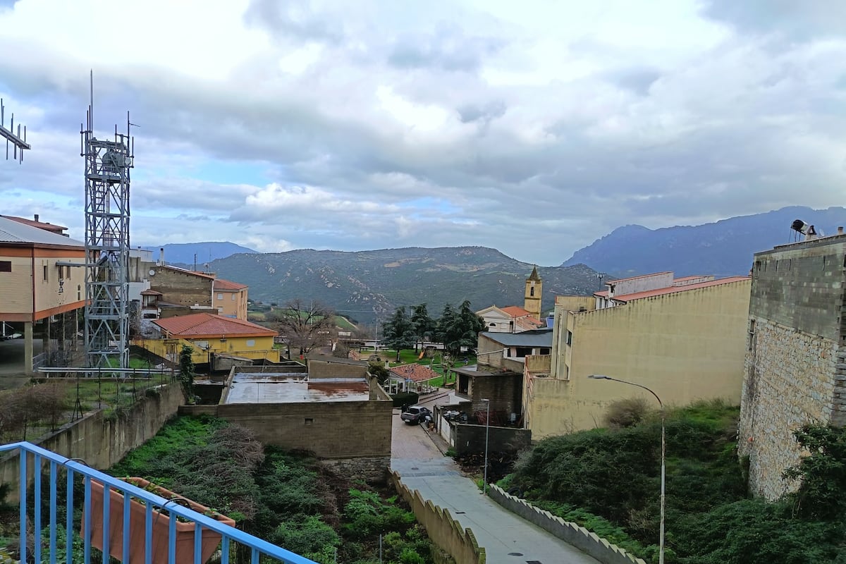 A view of a town with buildings, a church, and mountains in the background.