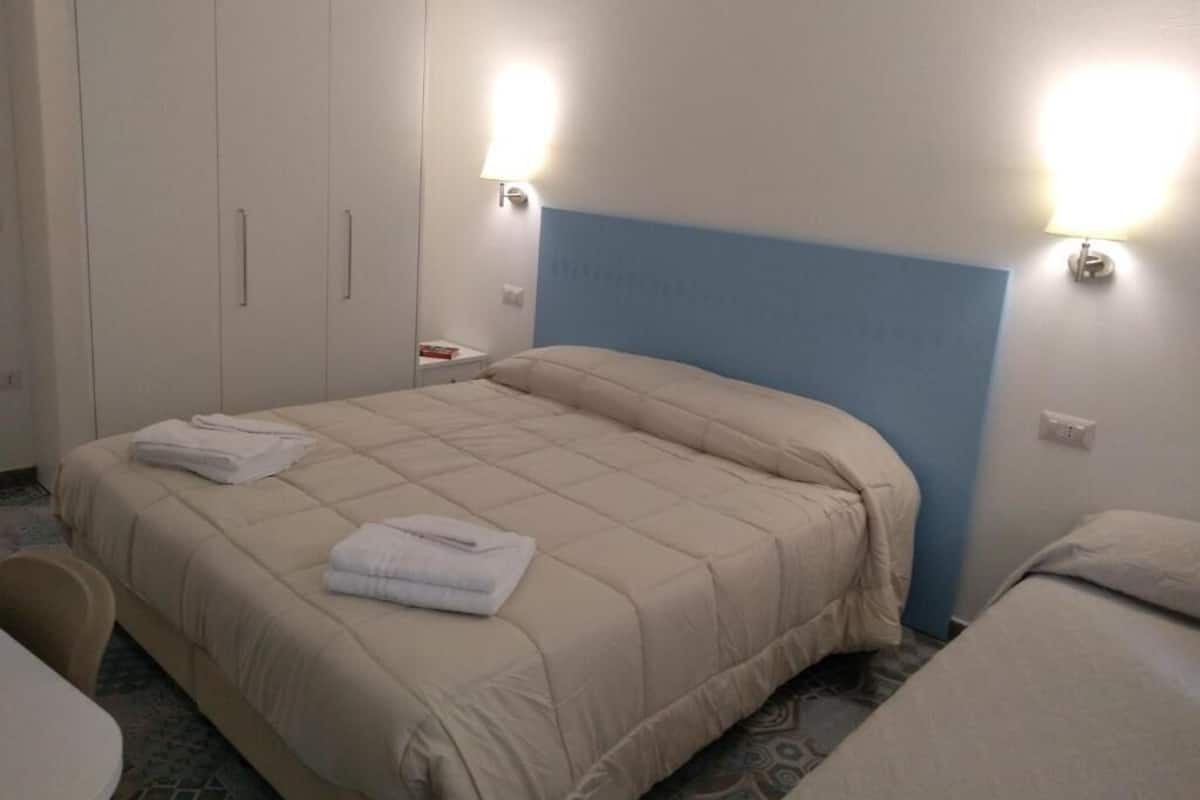 A hotel room with a bed, a wardrobe, and two wall-mounted lights.