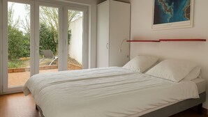 Une chambre à coucher avec un lit, une porte-fenêtre coulissante donnant sur un espace extérieur et une carte encadrée accrochée au mur.