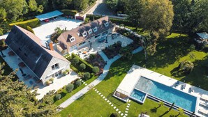 Une grande maison avec une piscine, un patio couvert et une pelouse bien entretenue.