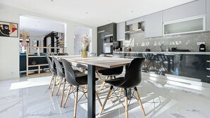 Une cuisine moderne dotée d’un grand îlot central, de chaises sombres et d’une table à manger en bois.
