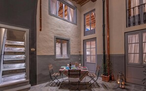 Zona pranzo con tavolo apparecchiato per quattro persone, circondato da sedie, con vista sul piano superiore attraverso una finestra.