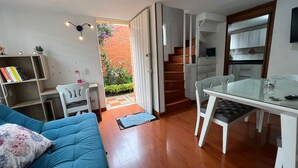 Un espace de vie compact comprenant un canapé, une table à manger et un coin cuisine.