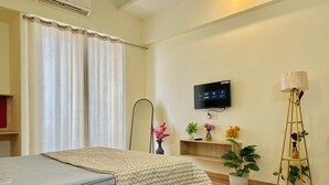Ein Hotelzimmer mit einem Bett, einem kleinen Tisch, einem Fernseher und Topfpflanzen.