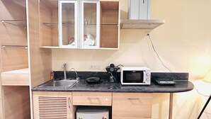 Eine kleine Küche mit Spüle, Mikrowelle und Kühlschrank.
