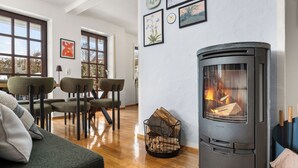 Ett mysigt vardagsrum med en vedeldad kamin, en soffa och en matplats med stolar.
