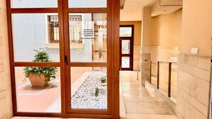 Ein Hotelkorridor mit einer Glastür, die auf einen Balkon mit einem Topfpflanzen und einen Kiesgarten führt.
