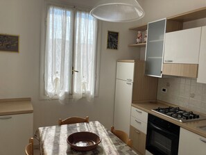 Eine Küche mit Esstisch, Stühlen, Herd, Backofen und Kühlschrank.