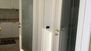 Una stanza con due porte bianche, una con un pannello in vetro satinato e l'altra con un pannello in vetro trasparente.