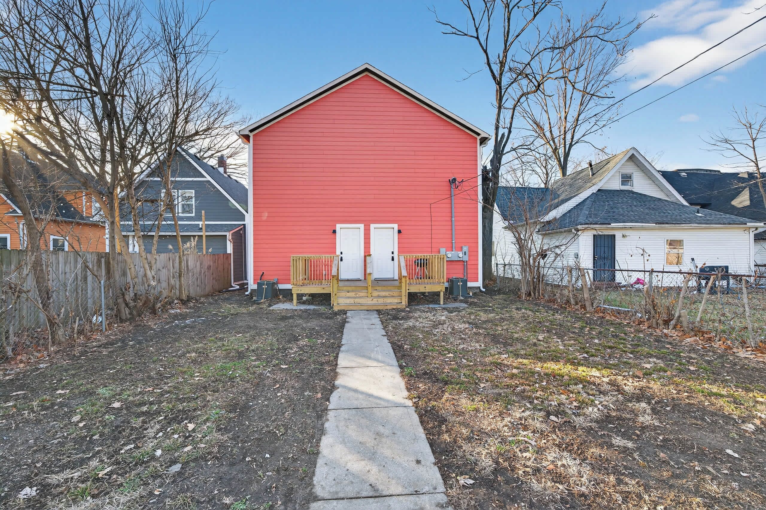 A red building with a wooden deck and a concrete pathway leading to it.