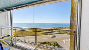 A balcony with a metal railing, a view of the sea, and a parking area with a white van. - Le Havre de Paix (Saint-Hilaire-de-Riez)