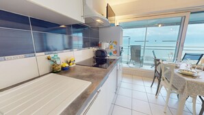 Eine moderne Küche mit großem Fenster, einem Essbereich mit Tisch für zwei Personen und Meerblick.