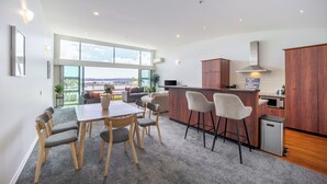 A modern kitchen with wooden cabinets, a stainless steel range hood, and a built-in microwave. - Harborfront Penthouse | Free Parking | Chill Vibes (Auckland)