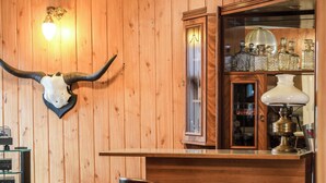 Baarialue, jossa on puupanelointi, seinälle kiinnitetty pääkallo ja kaksi baarijakkaraa.