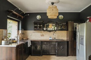 A kitchen with dark wooden cabinets, a white refrigerator, and a hanging rattan light fixture.