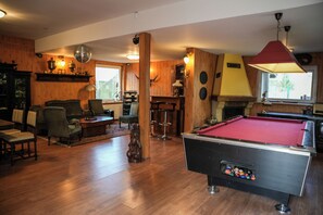 A spacious room with a pool table, wooden furniture, and a bar area.