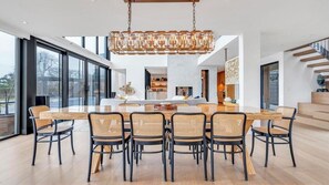 A modern dining area with a large rectangular table, six chairs, and a hanging light fixture. - Waterfront Southampton home with dock, pool, gym, great for groups (Southampton)