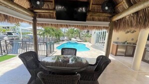A covered outdoor area with a pool, wicker furniture, and a TV screen. - Tremendous 2-bedroom house with AC in charming Key Largo (Key Largo)