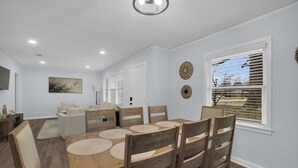 Un comedor con una mesa y sillas de madera, un sofá y un ventanal con persianas.
