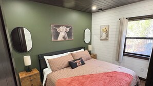 A bedroom with a bed, nightstands, a mirror, and wall art. - Cozy new construction 2-bedroom house in serene Harrison with all amenities. (Harrison)