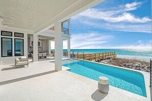 A modern pool area with a clear view of the ocean, a wooden deck, and a lounge area with seating. - The White Lowetus | Private Beach Access | Gulf Front | Private Pool (Santa Rosa Beach)