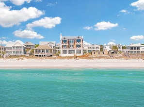 A beachfront property with multiple houses, including a prominent two-story house with large windows and a balcony. - The White Lowetus | Private Beach Access | Gulf Front | Private Pool (Santa Rosa Beach)