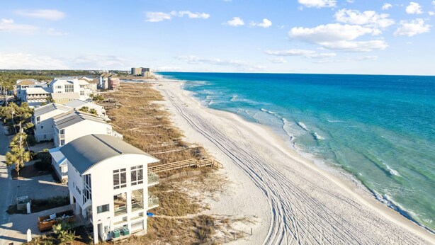 Ein Hotel an der Küste mit Blick auf den Strand, inklusive Sandstrand, Meer und einer Reihe von Gebäuden unter blauem Himmel.