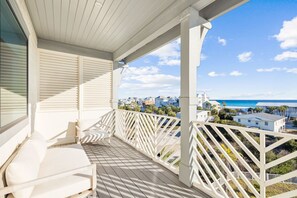 A balcony with white railings and a white ceiling, overlooking a coastal area with buildings and a clear sky. - Gather at the Gulf | Easy Beach Access | Private Pool | Golf Cart (Inlet Beach)